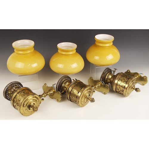 530A - Three brass oil lamp wall sconces, late 19th century, the Duplex burner reservoirs seated within cyl... 