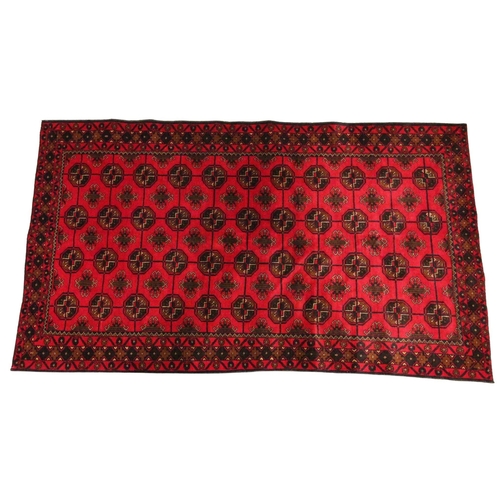 612 - An Afghan Belouch wool rug, the forty four octagonal medallions on a vibrant red ground, within four... 