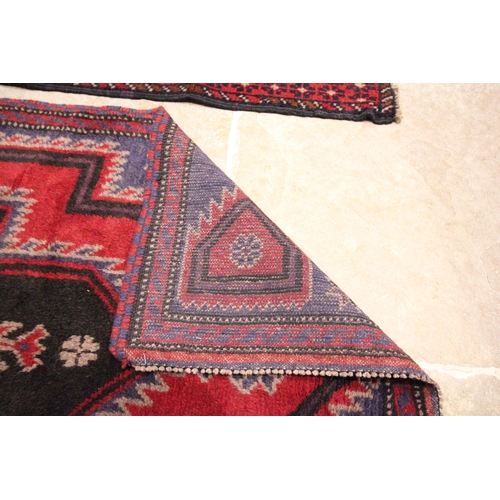 614 - A Caucasian wool rug, in red and blue colourways, with central graduated geometric medallions, enclo... 