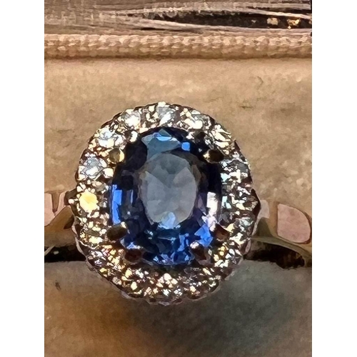 64 - A sapphire and diamond cluster ring, the central oval mixed cut cornflower blue sapphire measuring 8... 