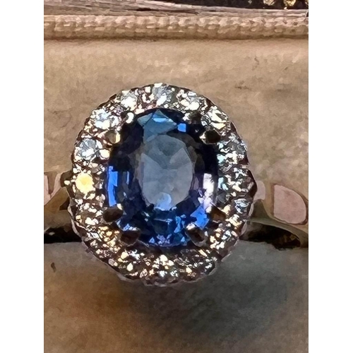 64 - A sapphire and diamond cluster ring, the central oval mixed cut cornflower blue sapphire measuring 8... 