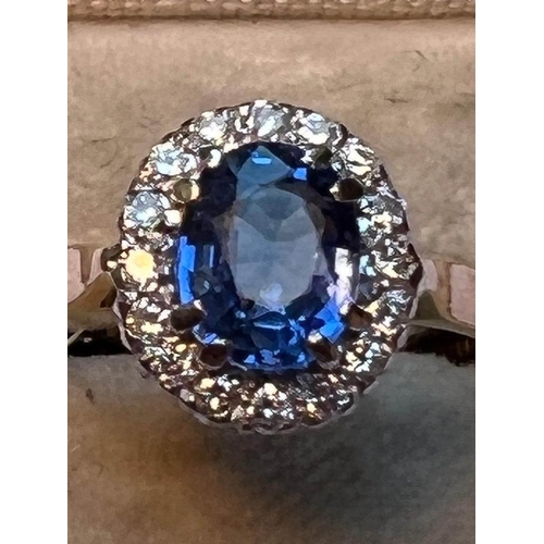 64 - A sapphire and diamond cluster ring, the central oval mixed cut cornflower blue sapphire measuring 8... 