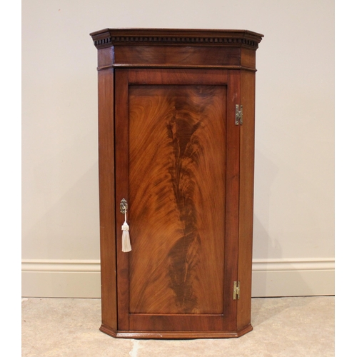 751 - A George III and later mahogany corner cupboard, the hinged recessed panel door opening to reveal an... 