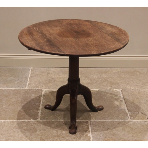 757 - A George III oak tilt-top tripod table, the circular plank top raised upon a ring turned gun barrel ... 