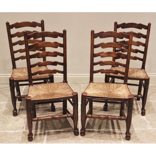 807 - A set of four ash ladder back kitchen chairs, 19th century, each with four shaped rungs over an enve... 