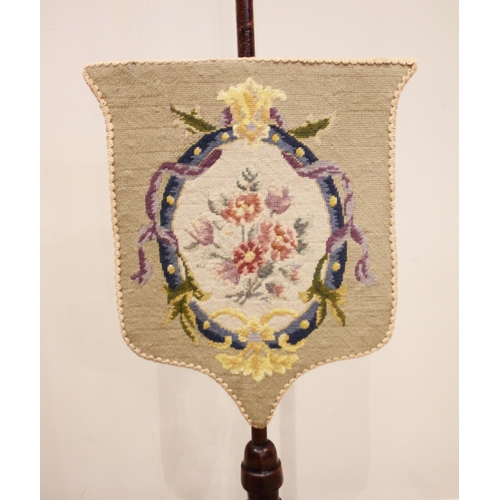 827 - A Victorian mahogany pole screen, the shield shaped floral tapestry screen upon a slender pole and t... 