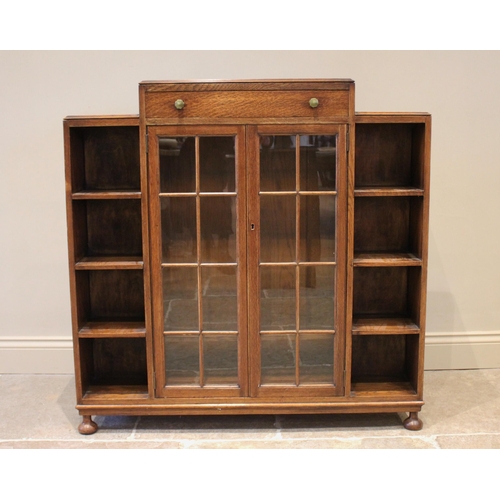 854 - An Art Deco glazed oak bookcase, the architectural shaped top containing frieze drawer with Bakelite... 