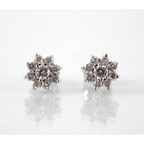 133 - A pair of diamond floral cluster earrings, each comprising a central round brilliant cut diamond wei... 