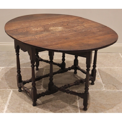 716 - An 18th century oak drop leaf dining table, the oval plank top above a single frieze drawer, upon ri... 