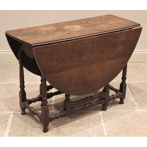 716 - An 18th century oak drop leaf dining table, the oval plank top above a single frieze drawer, upon ri... 