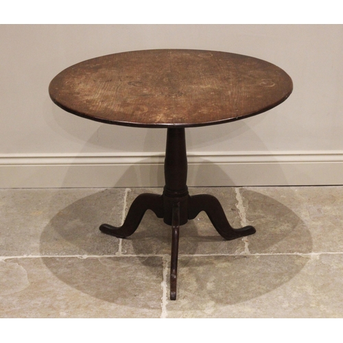 738 - A George III oak tripod table, the circular top raised upon a ring turned baluster column extending ... 