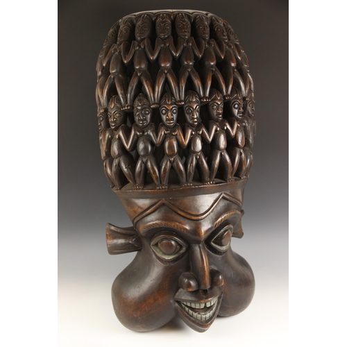 442 - A large Bamileke carving, Cameroon, 20th century, carved depicting a mask below an abundance of figu... 