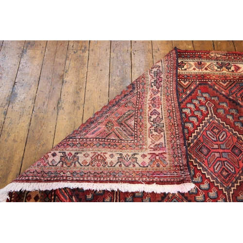 618 - A large terracotta ground Persian runner, in red, blue and ivory colourways, the seven lozenge shape... 