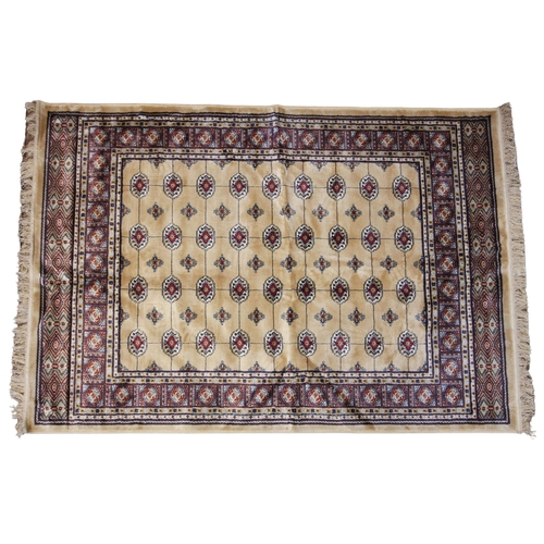 620 - A gold ground Kashmir Bokhara design rug, the central field with rows of Bokhara type gulls united b... 