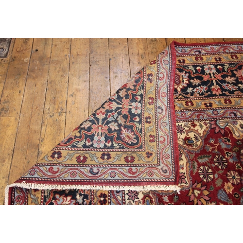 621 - A large deep red ground Persian carpet, the central floral medallion enclosed by conforming spandrel... 