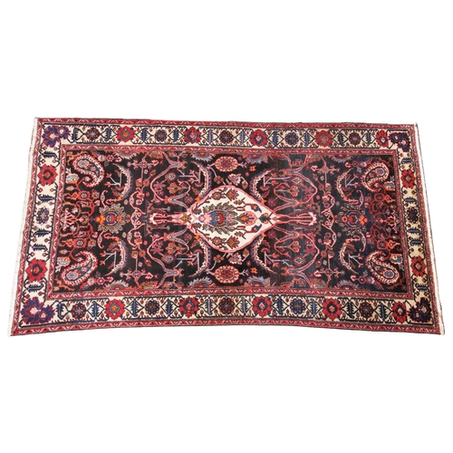 623 - A deep ground Persian Ardebil carpet, in orange, brown and red colourways, the central petal shaped ... 