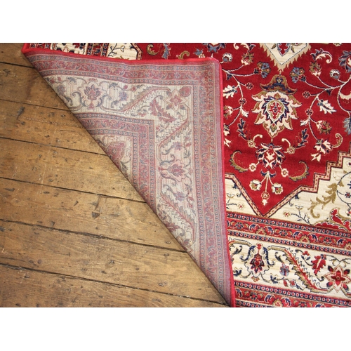 626 - A vibrant red ground Kashmir rug, the traditional medallion design with conforming serrated spandrel... 