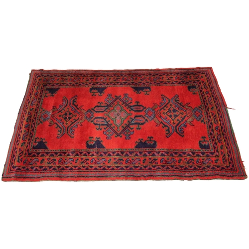 627 - A Turkish hand knotted wool rug, in red, green and blue colourways, the three open work medallions u... 