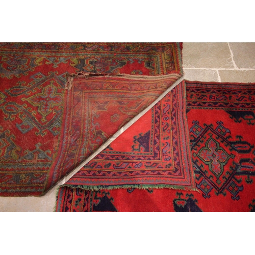 627 - A Turkish hand knotted wool rug, in red, green and blue colourways, the three open work medallions u... 