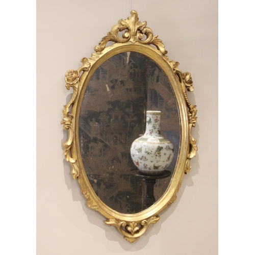 703 - A giltwood Rococo style wall mirror, 20th century, the oval mirrored plate within a moulded frame ap... 