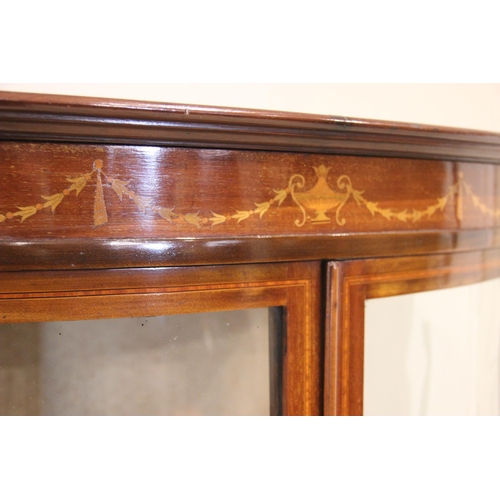 858 - An Edwardian mahogany bowfront display cabinet, the frieze inlaid with an Adam style urn and harebel... 