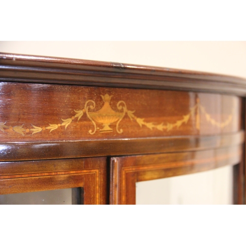 858 - An Edwardian mahogany bowfront display cabinet, the frieze inlaid with an Adam style urn and harebel... 