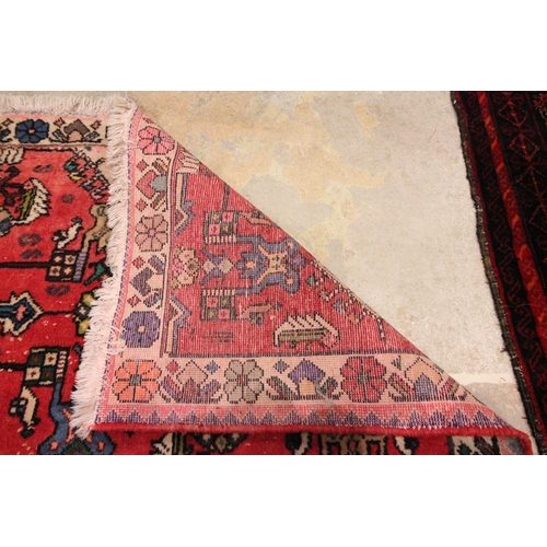 615 - An Afghan wool rug, in red and blue colourways, the three central hexagonal red medallions on a blue... 