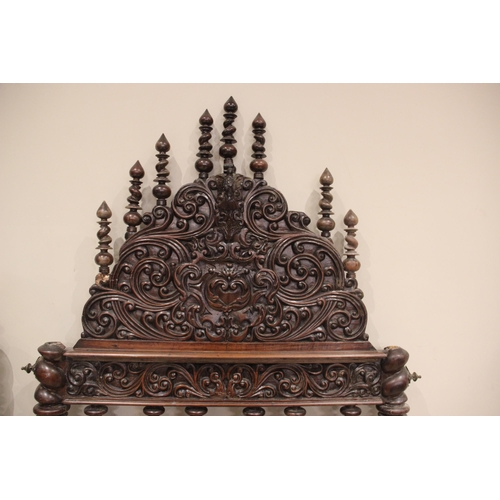 737 - A 17th century style German carved walnut bed frame, the spire shaped headboard with carved scroll d... 