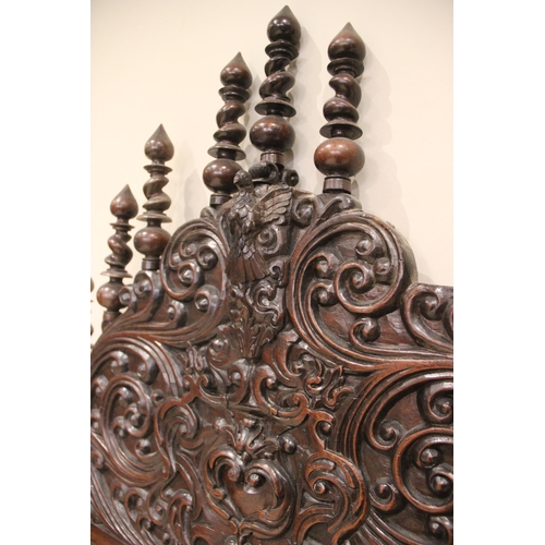 737 - A 17th century style German carved walnut bed frame, the spire shaped headboard with carved scroll d... 