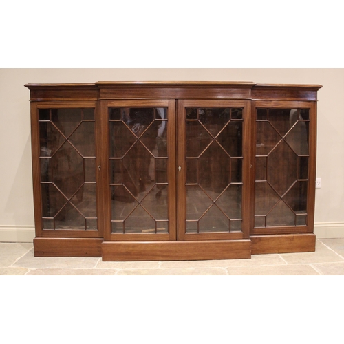 832 - An Edwardian mahogany breakfront bookcase, the moulded top above a pair of astragal glazed doors fla... 