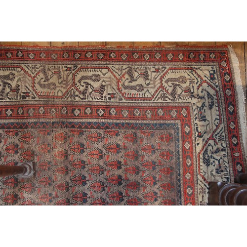 633 - A Persian carpet in red, black and ivory colourways, the central field with repeating leaf motifs, w... 