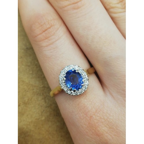 64 - A sapphire and diamond cluster ring, the central oval mixed cut cornflower blue sapphire measuring 8... 