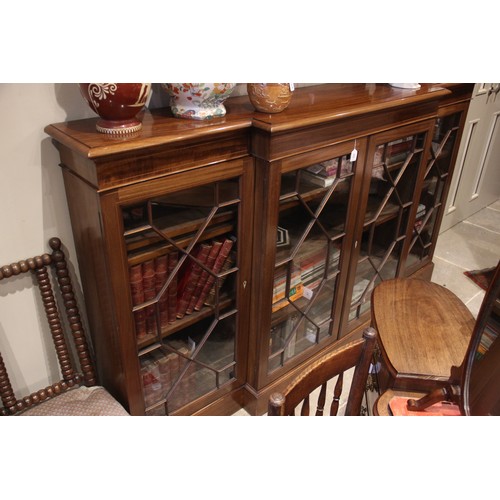 832 - An Edwardian mahogany breakfront bookcase, the moulded top above a pair of astragal glazed doors fla... 