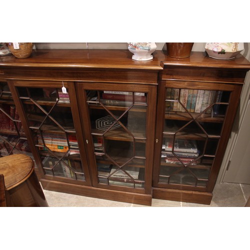 832 - An Edwardian mahogany breakfront bookcase, the moulded top above a pair of astragal glazed doors fla... 