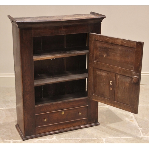 615 - An oak spice cupboard, mid 18th century, the moulded cornice above a tri-panel cupboard door opening... 