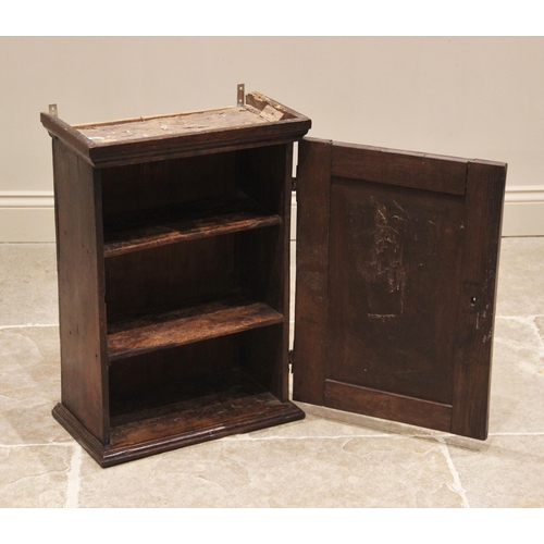 625 - An 18th century oak spice cupboard, the moulded cornice above a single panelled door opening to two ... 