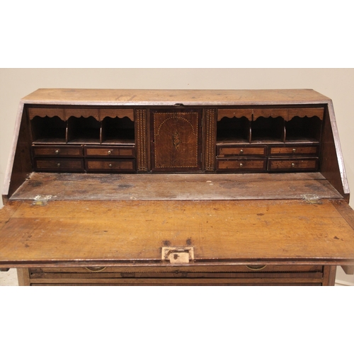 629 - A George III oak and mahogany crossbanded bureau, the fall front centred with an inlaid cartouche de... 