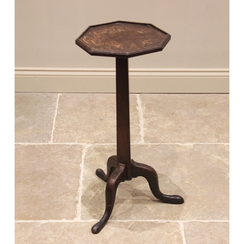 630 - A George III oak candle stand, the octagonal top with a moulded rim, upon a tri-form tapering column... 