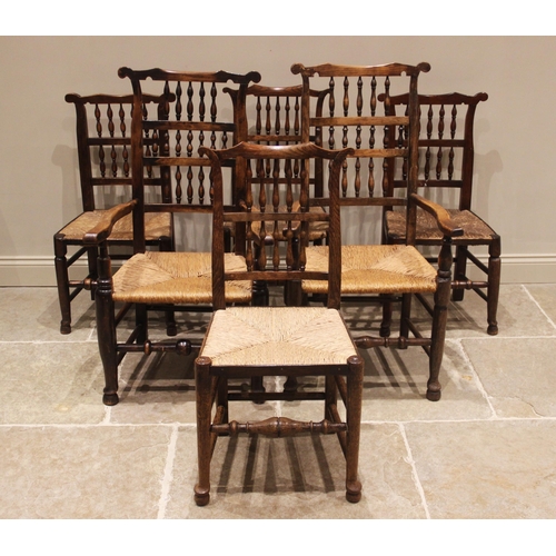 637 - A matched set of twelve ash and elm rush seat spindle back chairs, 19th century, each with a cupids ... 