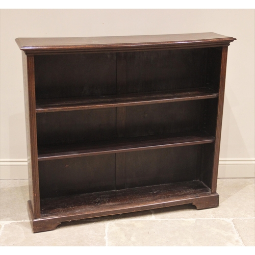 698 - An Edwardian oak open bookcase, the rectangular moulded top upon fluted uprights enclosing the two a... 