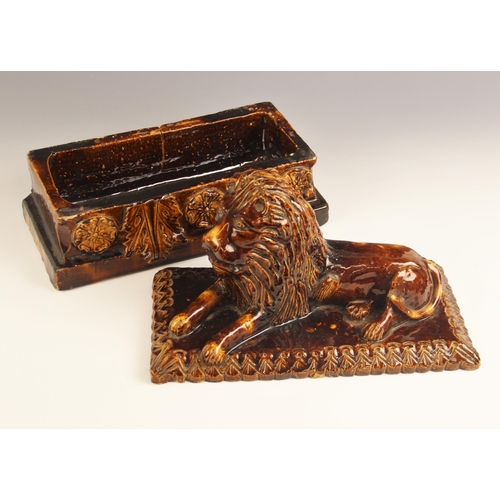 477 - An English treacle glazed earthenware tobacco box of large proportions, 19th century, the cover mode... 