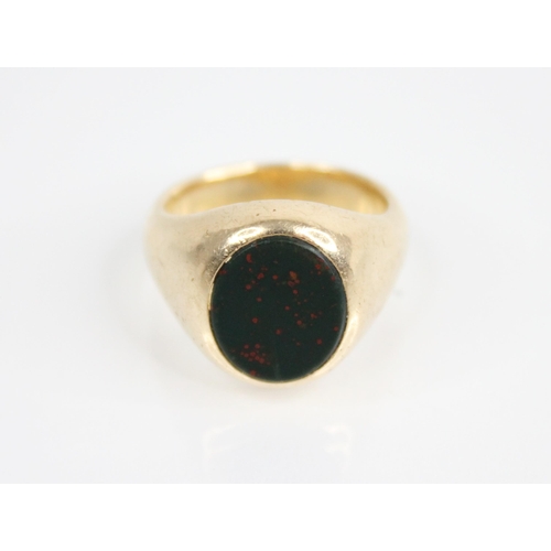 140 - A bloodstone set signet ring, the central oval bloodstone panel measuring 12.3mm x 10.3mm, continuin... 