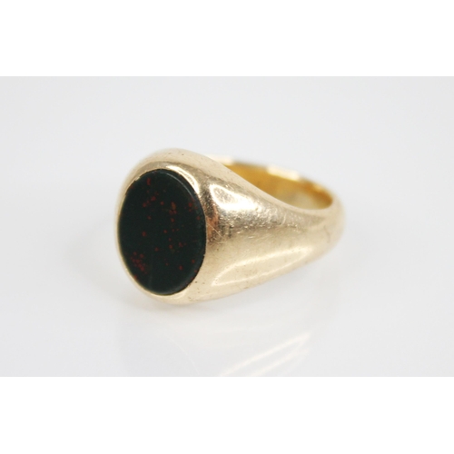 140 - A bloodstone set signet ring, the central oval bloodstone panel measuring 12.3mm x 10.3mm, continuin... 