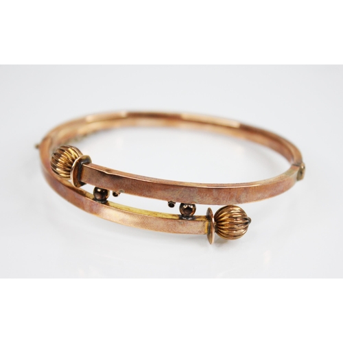 194 - A Victorian gold coloured hinged bangle, the cross over front section with reeded spherical terminal... 