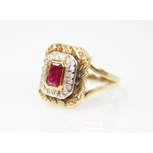 211 - A ruby and diamond cluster ring, the central emerald cut ruby measuring 6mm x 3.5mm, set to a surrou... 