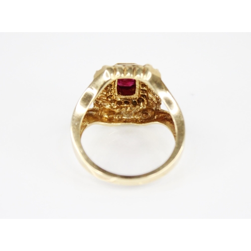 211 - A ruby and diamond cluster ring, the central emerald cut ruby measuring 6mm x 3.5mm, set to a surrou... 