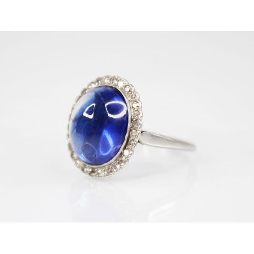 192 - An early 20th century sapphire and diamond cluster ring, the central oval sapphire cabochon measurin... 