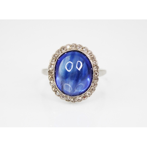 192 - An early 20th century sapphire and diamond cluster ring, the central oval sapphire cabochon measurin... 