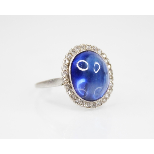 192 - An early 20th century sapphire and diamond cluster ring, the central oval sapphire cabochon measurin... 