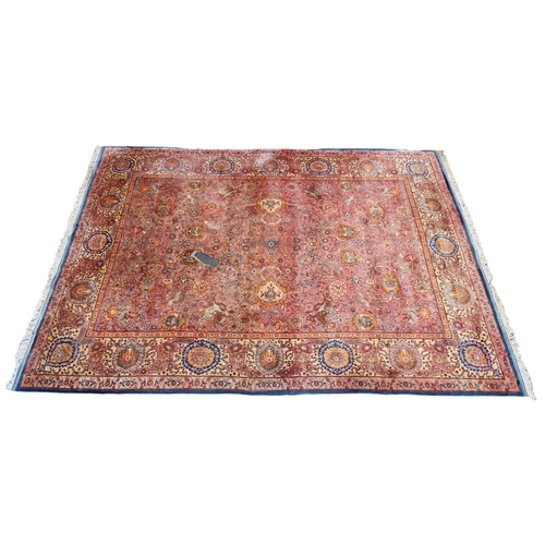 581 - A large Persian pattern wool rug, in blue, pink and yellow colourways, the central field applied wit... 